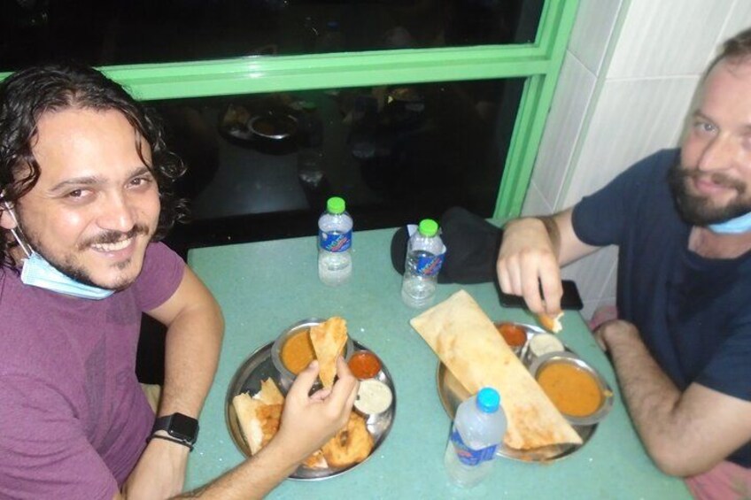 Two people sitting at a table with food and drinks. 3