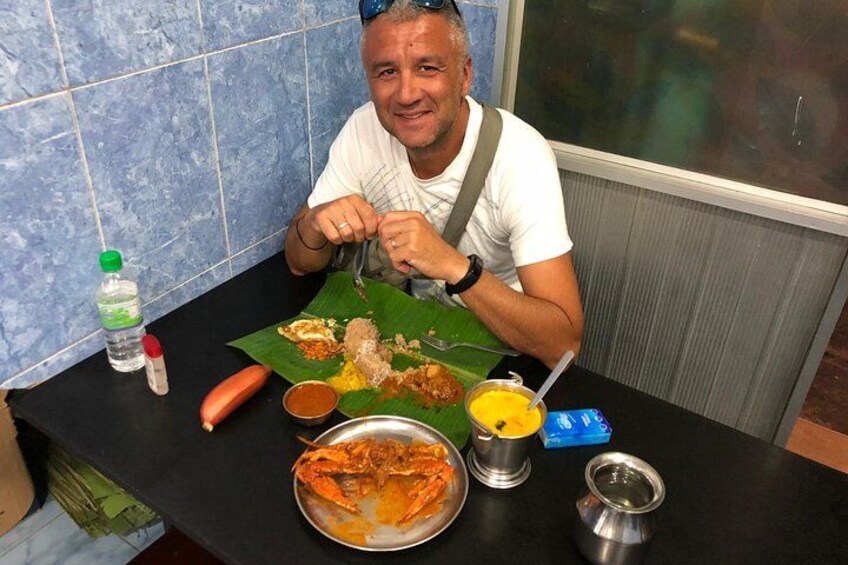 A person sitting at a table with a variety of dishes, including a large plate of food, a bowl of soup, and several small containers. 4
