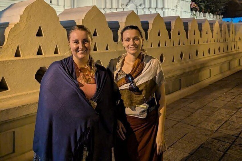 Twee personen staan voor een decoratieve muur met geometrische patronen. 2