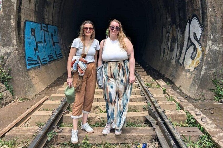 Twee personen staan op spoorrails met graffiti op de tunnelwanden. 3