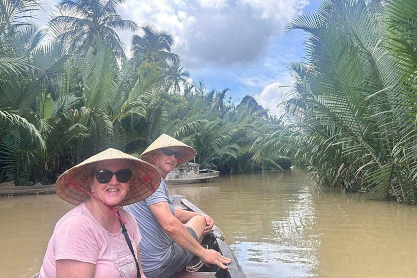 Twee personen in een boot op een rivier, omringd door palmbomen. 2