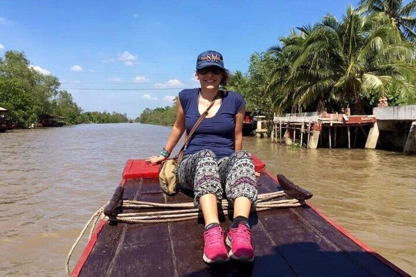 A person sitting on a boat in a river with palm trees in the background. 5