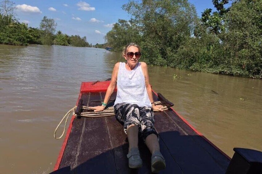 A person sitting on a boat in a river surrounded by greenery. 4