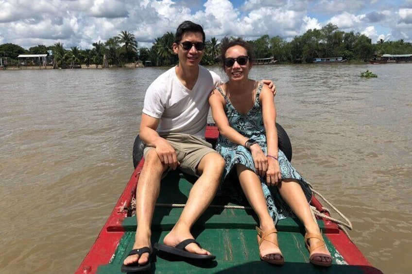 Two people sitting on a boat in a river surrounded by greenery. 3