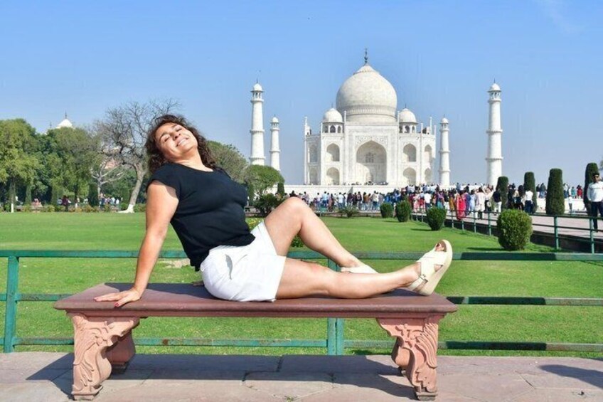 A person sitting on a bench with the Taj Mahal in the background. 2