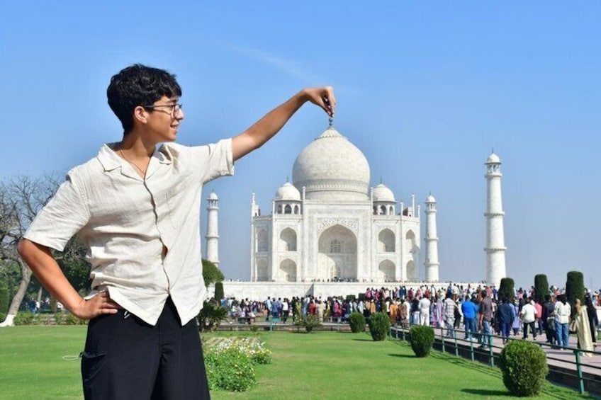 A person pointing at the Taj Mahal with a crowd in the background. 3