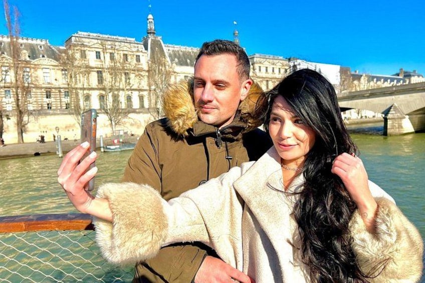 A couple taking a selfie with a historic building and a river in the background. 2