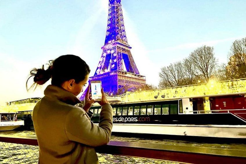 A person taking a photo of the Eiffel Tower with a river in the foreground. 3