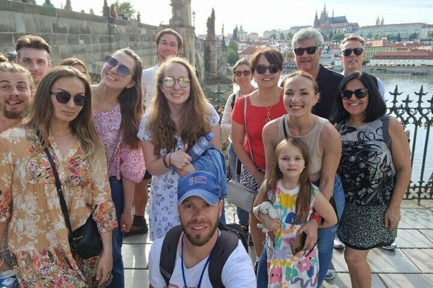 A group of people posing for a photo in front of a historic building with a river in the background. 2