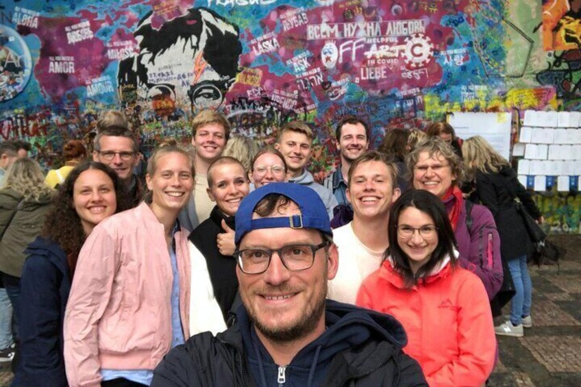 A group of people posing in front of a graffiti-covered wall with various colorful designs and text. 3