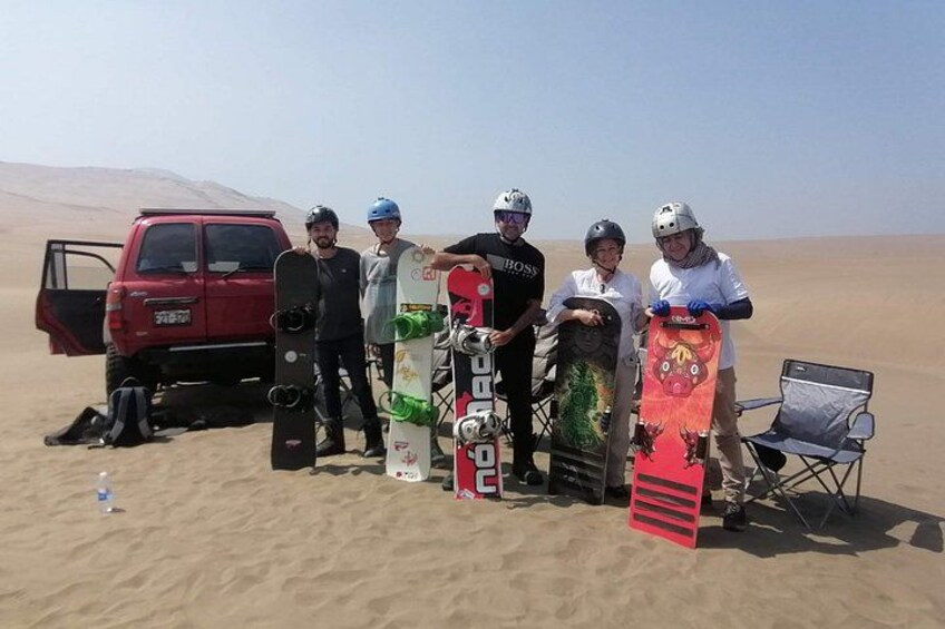 A group of people with snowboards in a desert landscape. 5