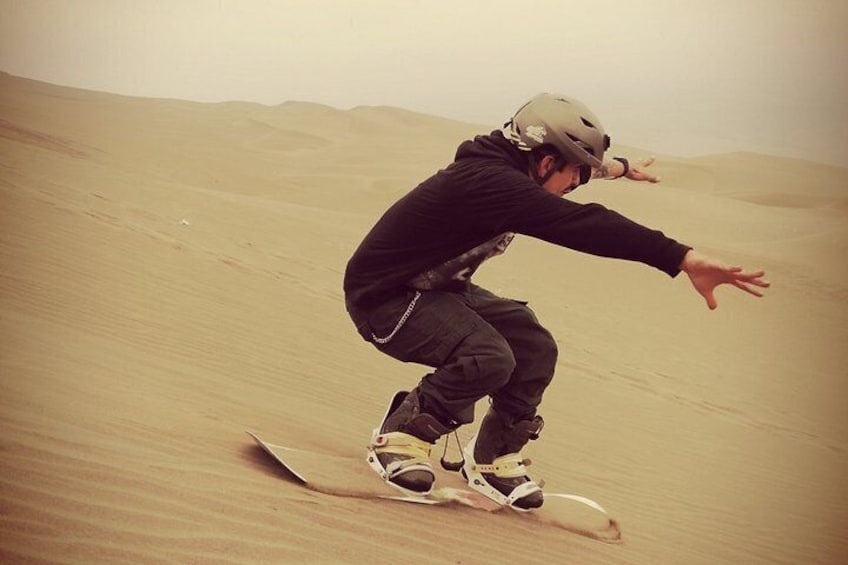 A person snowboarding down a sandy slope. 1