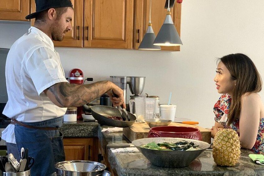 A person cooking in a kitchen with wooden cabinets, a granite countertop, and various cooking utensils and ingredients. 4