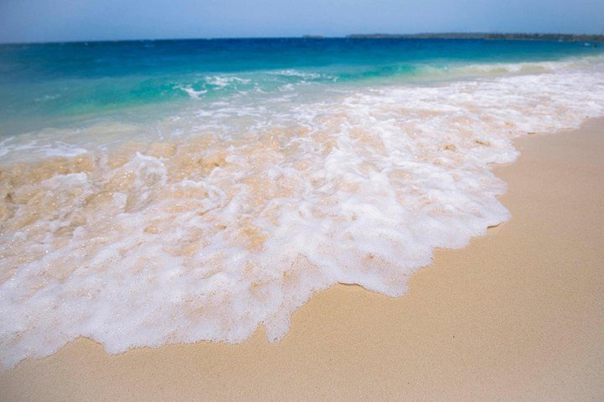 A beach with foamy waves and clear turquoise water. 2
