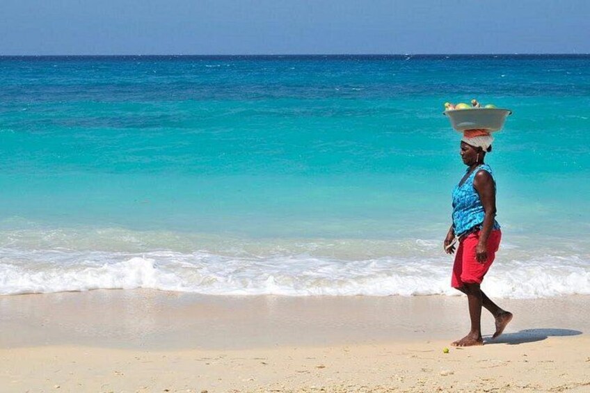 A person walking on a beach with a bowl on their head. 5