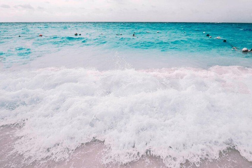 A beach with waves crashing onto the shore and people swimming in the water. 3