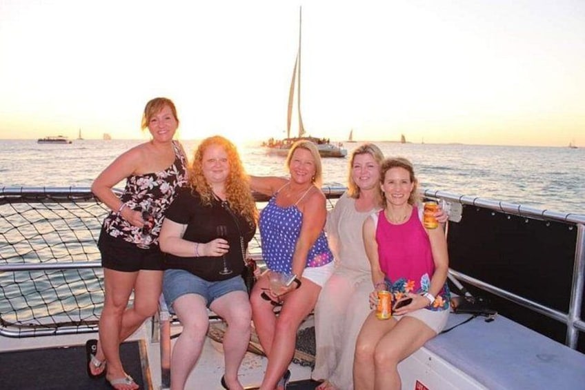 Un grupo de personas en un barco, con un velero al fondo. 3