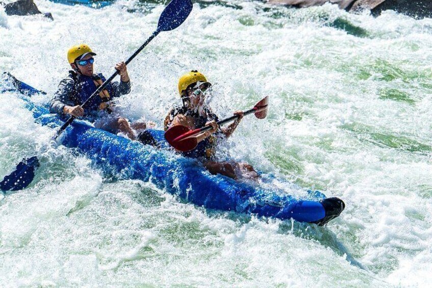 Two people kayaking in a blue raft on a river. 4
