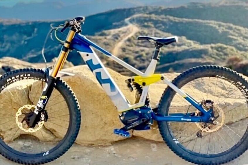 A mountain bike on a rocky surface with a mountainous landscape in the background. 3