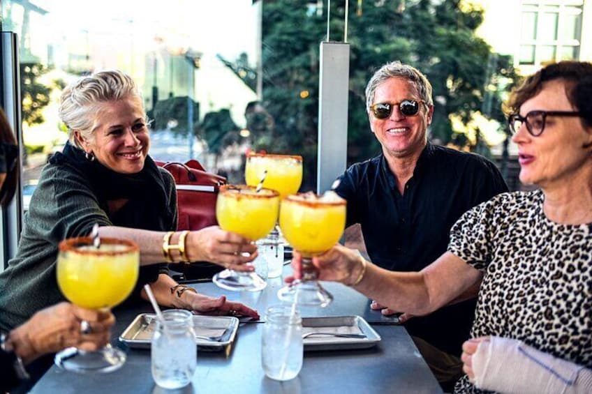 A group of people toasting with drinks at an outdoor table. 1