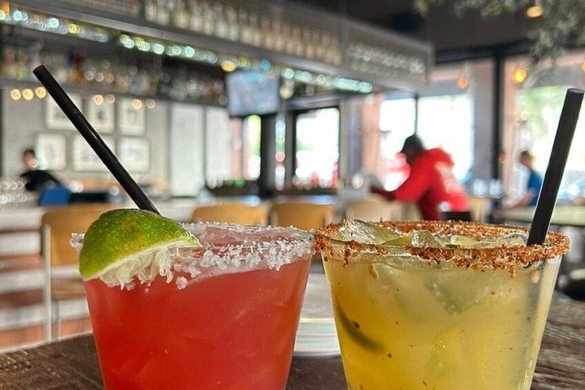 Two cocktails with lime garnishes on a bar counter. 3