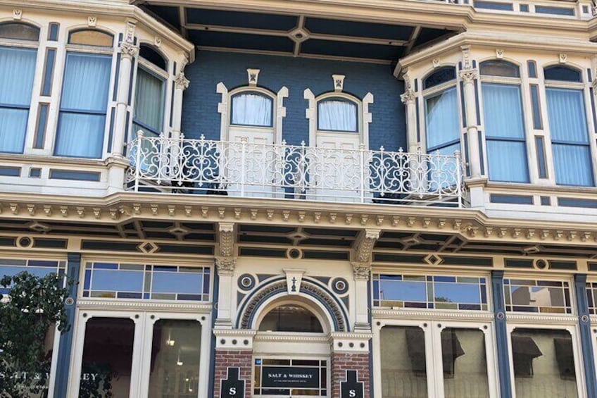 A building with ornate architectural details, including a balcony with white railings and a sign that reads 'SALT & WHISKY.' 4