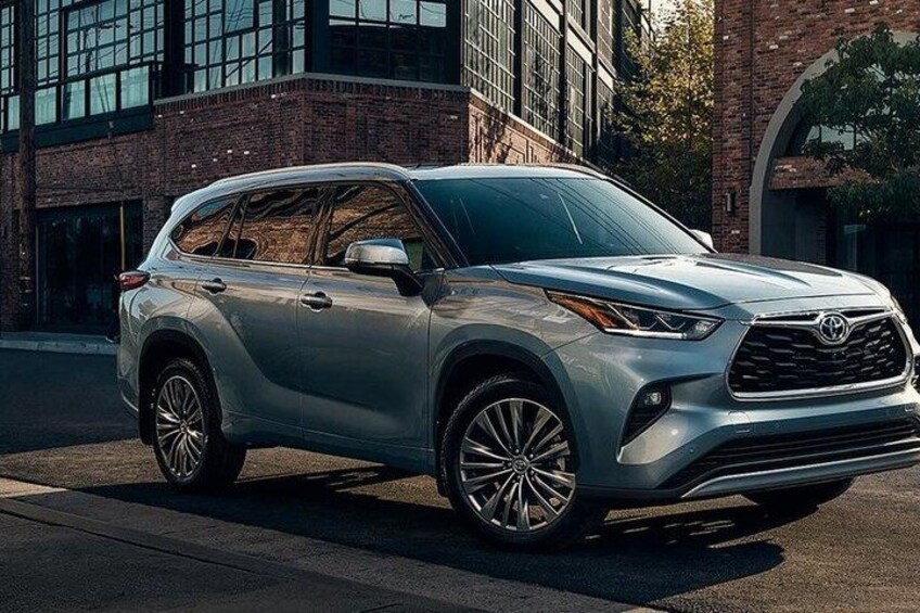 A silver SUV parked on a street with a brick building in the background. 2