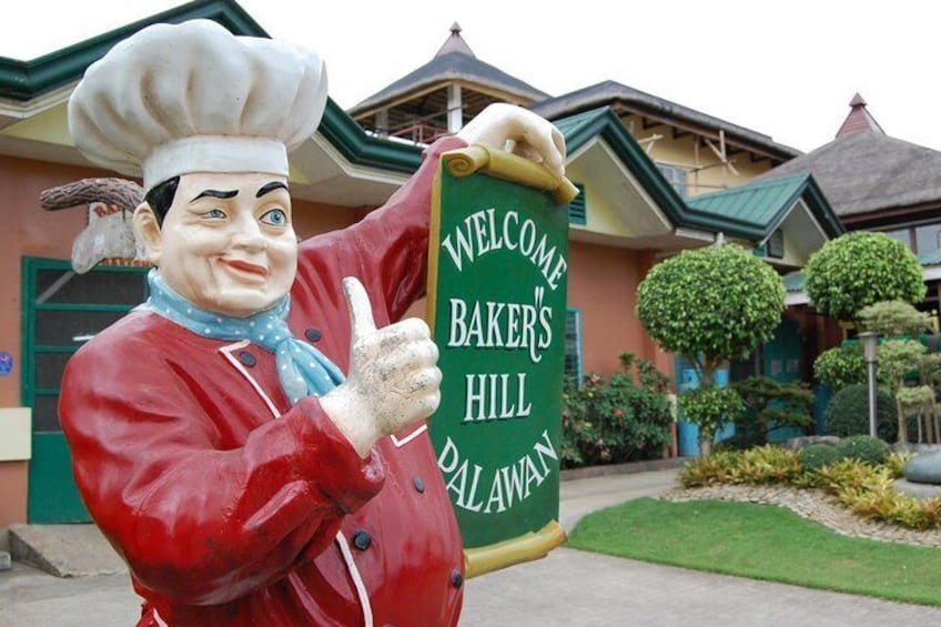 Une grande statue d’un chef cuisinier tenant une pancarte sur laquelle on peut lire : « Bienvenue à Baker’s Hill Dalawaan. » 3