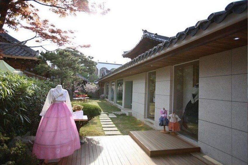 A traditional Japanese building with a wooden deck and a pink dress on a mannequin. 2