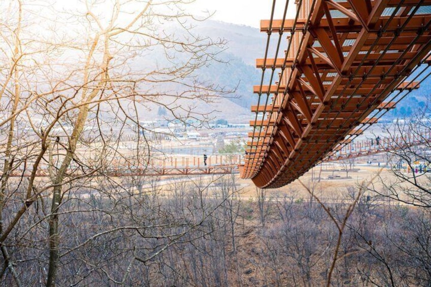 A bridge with a metal framework, surrounded by leafless trees and a mountainous backdrop. 1