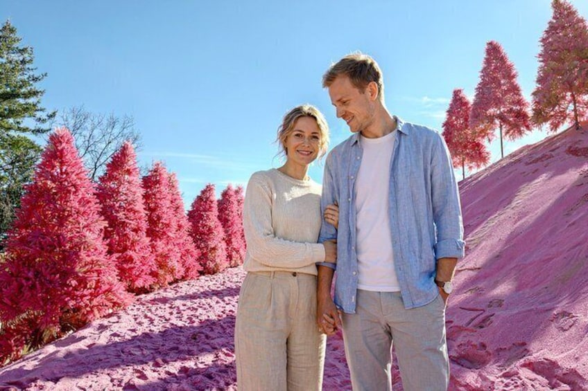 A couple standing on a sandy path with red foliage trees in the background. 4