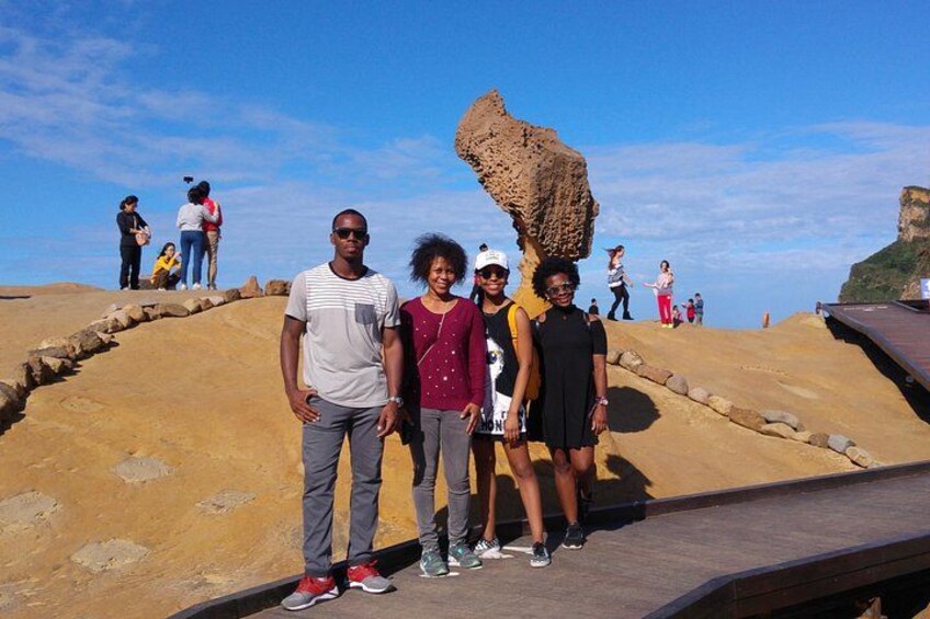 A group of people standing on a rocky outcrop with a large rock formation in the background. 3