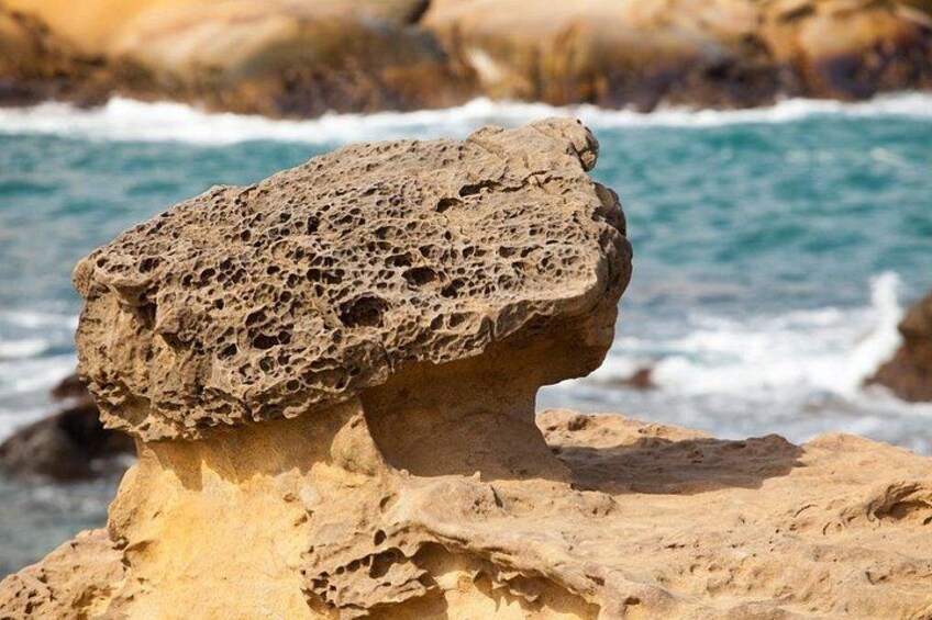 A rock formation with a hollow top, located near a body of water. 5