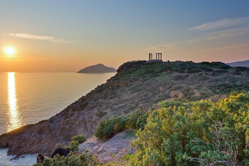 A coastal landscape with a sunset, rocky terrain, and ancient ruins. 2