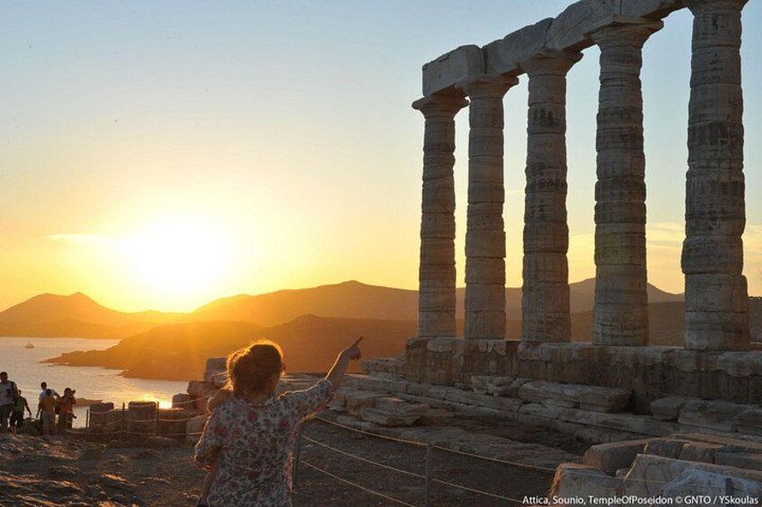 Ancient stone columns, a sunset, and a person pointing at the columns. 3