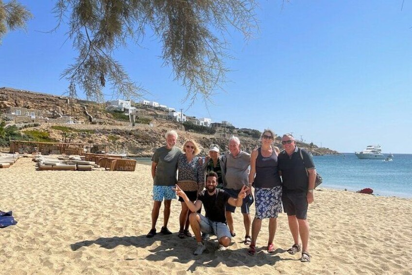 Un grupo de personas en una playa arenosa con un bote en el agua y edificios al fondo. 5