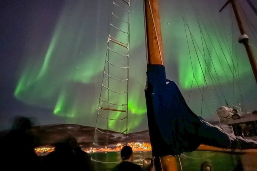 A sailboat with a ladder, a person, and the Northern Lights in the background. 2