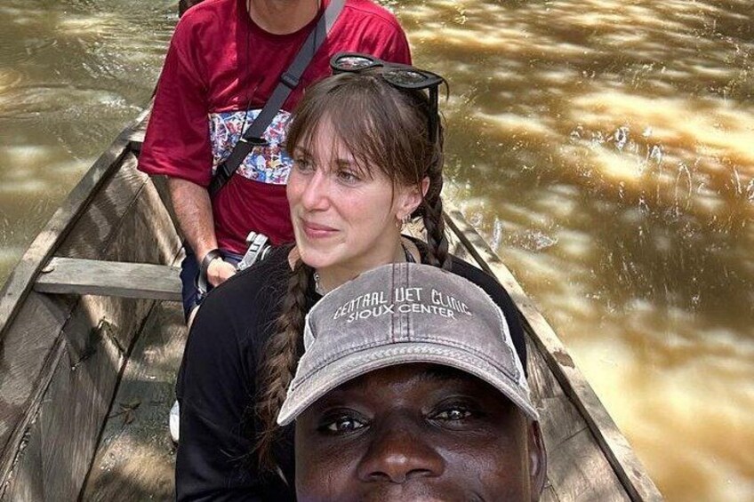 A wooden boat on a river with people wearing hats and a red shirt. 4