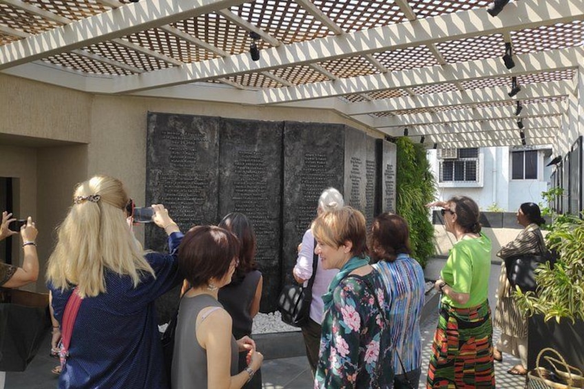 A group of people taking photos in front of a wall with inscriptions. 2