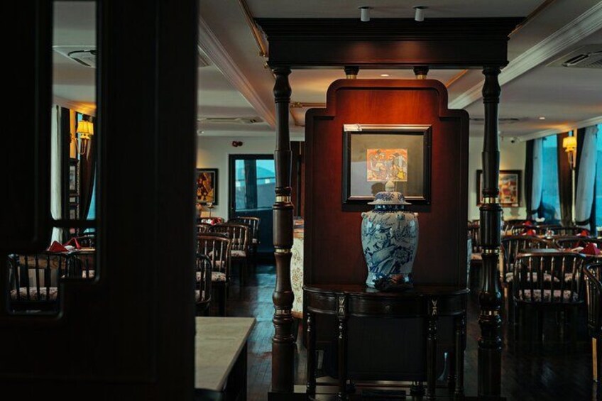 Une pièce faiblement éclairée, avec un grand vase posé sur un piédestal, entouré de chaises et de tables. 4