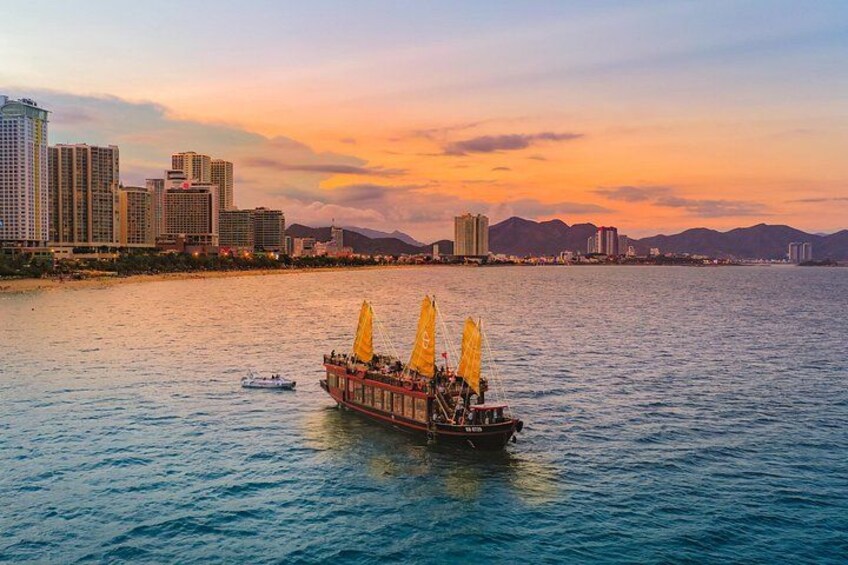 A riverboat with yellow sails, a city skyline, and mountains in the background. 1