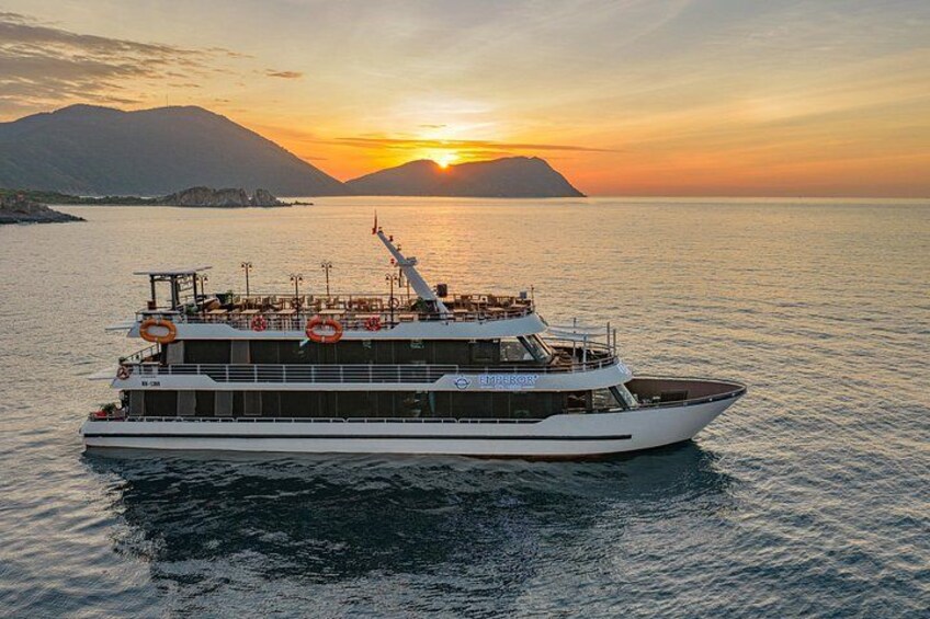 A large white boat with lifebuoys on the deck, sailing on calm waters during sunset. 5