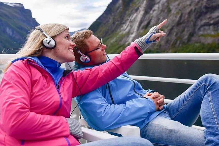 Two people sitting on a bench, wearing headphones, with a mountainous landscape in the background. 4