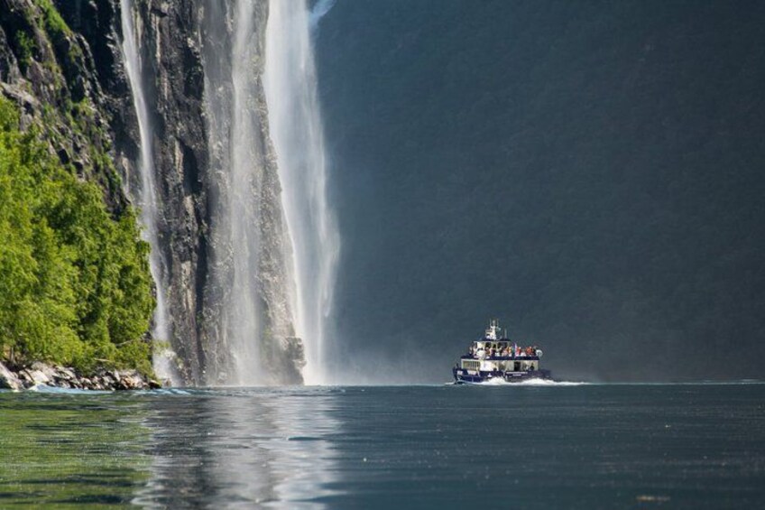 A boat on calm water near a large waterfall. 2
