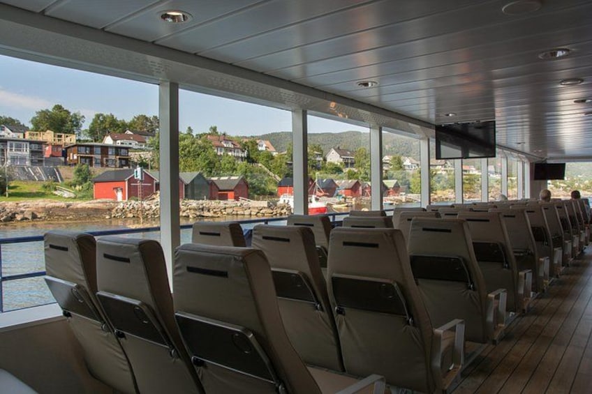 A ferry interior with rows of seats and a view of a coastal village. 2