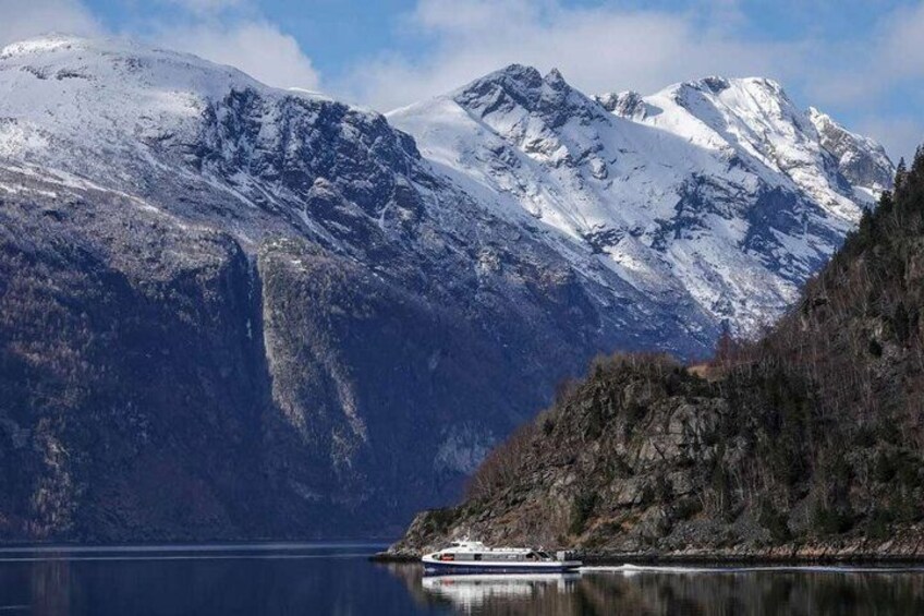 A lake with a boat, snow-covered mountains, and a forested area. 3