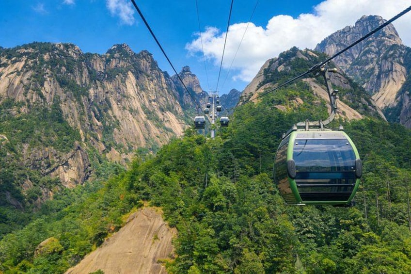 A cable car in a mountainous area with lush greenery and rocky cliffs. 3