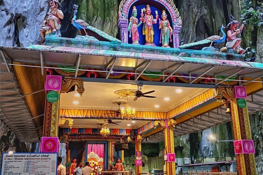 A temple with colorful statues, a shrine, and a ceiling fan. 3