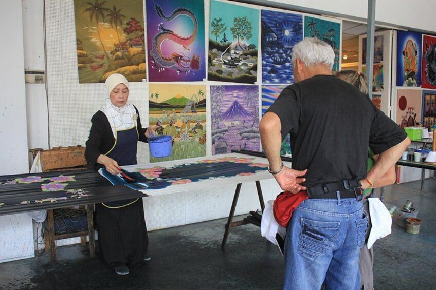 An art studio with a person painting on a canvas, a table with art supplies, and a wall with various artworks. 2