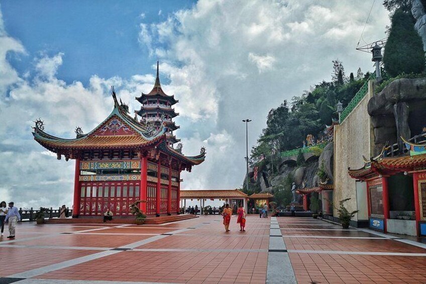 Una pagoda china tradicional con múltiples niveles, un patio empedrado y una ladera rocosa al fondo. 5